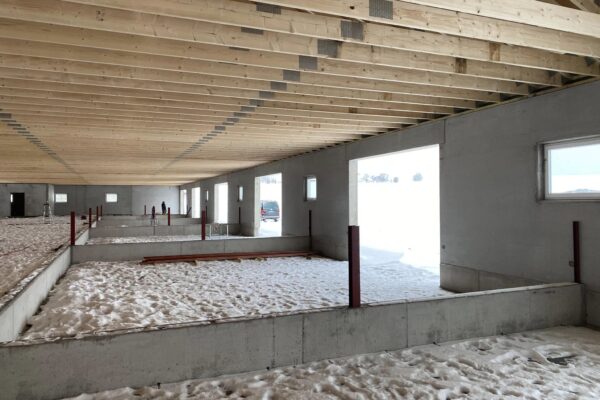 Prefab landbruksbygg under bygging, innendørs med stålrammer, isolasjon og isolert betonggulv, klar for innredning og bruk i jordbruks- og landbruksformål.