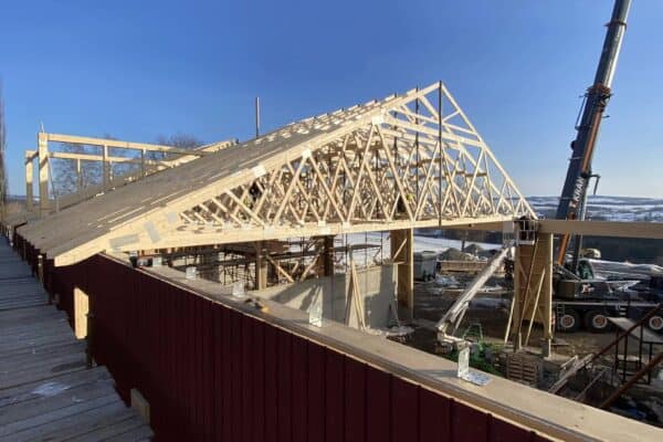 Husbygg under oppføring med trestender og reisverk for landbruk og landbruksbygg i Innlandet. Konstruksjonen viser solid rammeverk og skogbrukskonsept tilpasset landbruksnæringen.