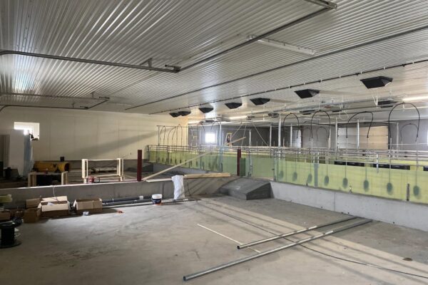 Egnede bilder av landbruks- og fjøsbygg under oppføring, med arbeidsområde og konstruksjonsmaterialer.