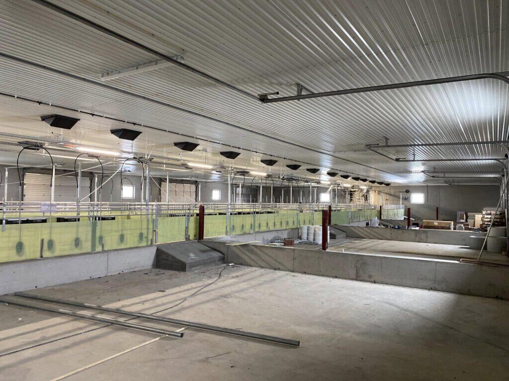 Industrielt landbrukssal under bygging med moderne ventilasjons- og oppvarmingssystem, ferdigstillelse for landbruksutstyr og drift. Fokus på kvalitet og funksjonalitet for landbruksbygninger i Innlandet.