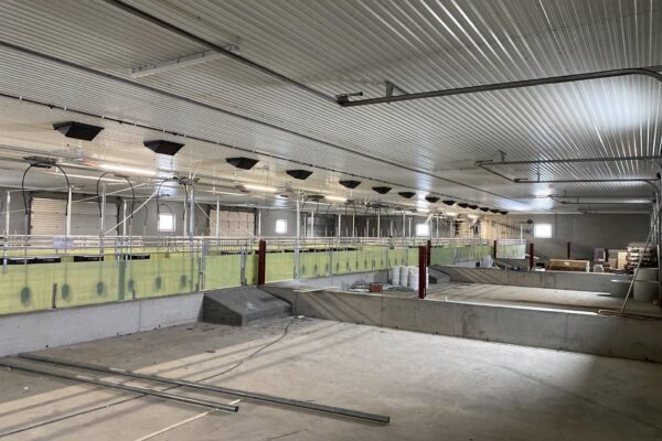 Industrielt landbrukssal under bygging med moderne ventilasjons- og oppvarmingssystem, ferdigstillelse for landbruksutstyr og drift. Fokus på kvalitet og funksjonalitet for landbruksbygninger i Innlandet.