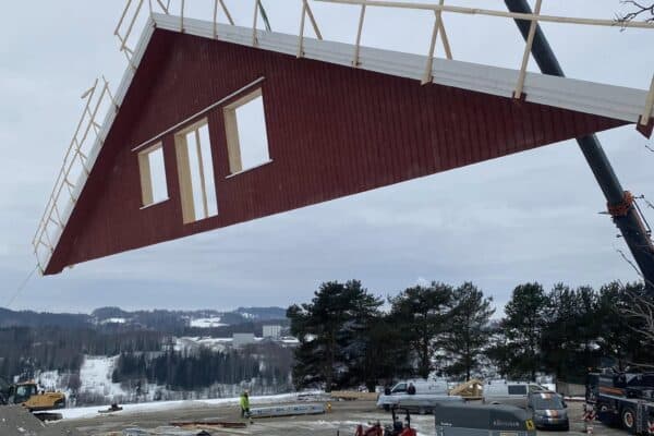 Hyttebygging under montering med kran i snøvær, landbruksbygg i Innlandet, krevende byggprosjekt, erfarne entreprenører, høykvalitets landbruks- og takbygg.