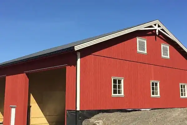 Tradisjonelt landbruksbygg i tre med rød maling, nær landbruk og gårdsdrift i Innlandet, tilpasset landbruksbehov.